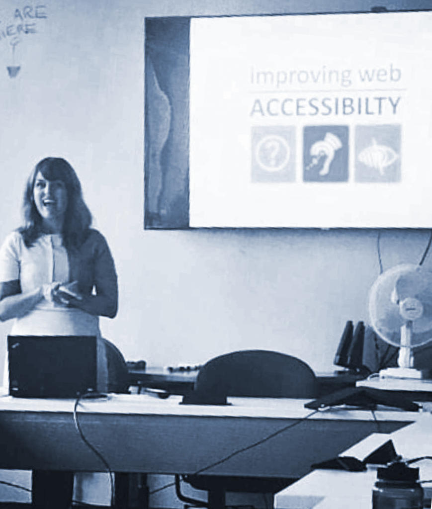 A person stands in a meeting room and gives a presentation on "Improving web accessibility"